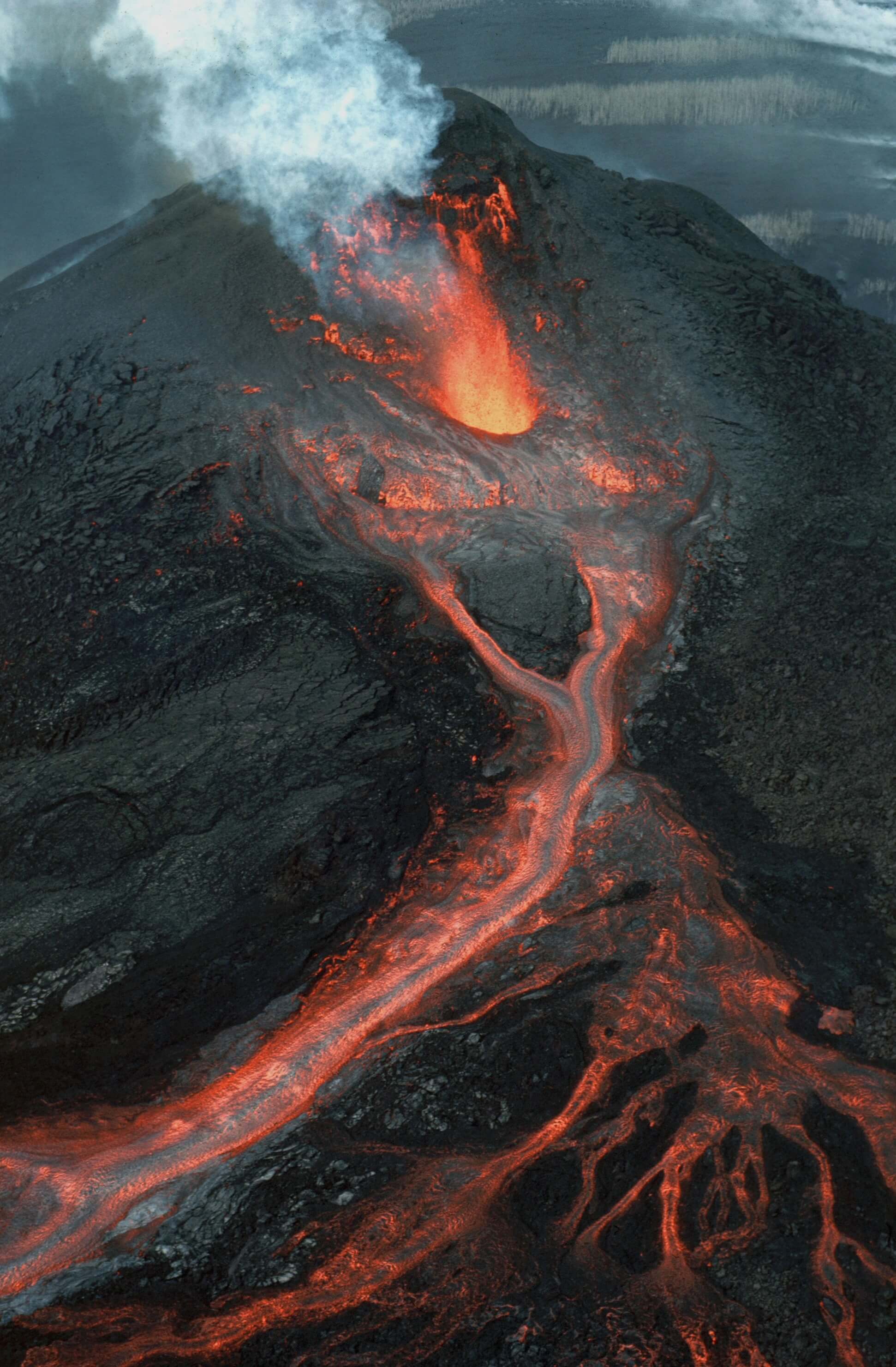 Aerial view of an active volcano with bright lava rivers and steam