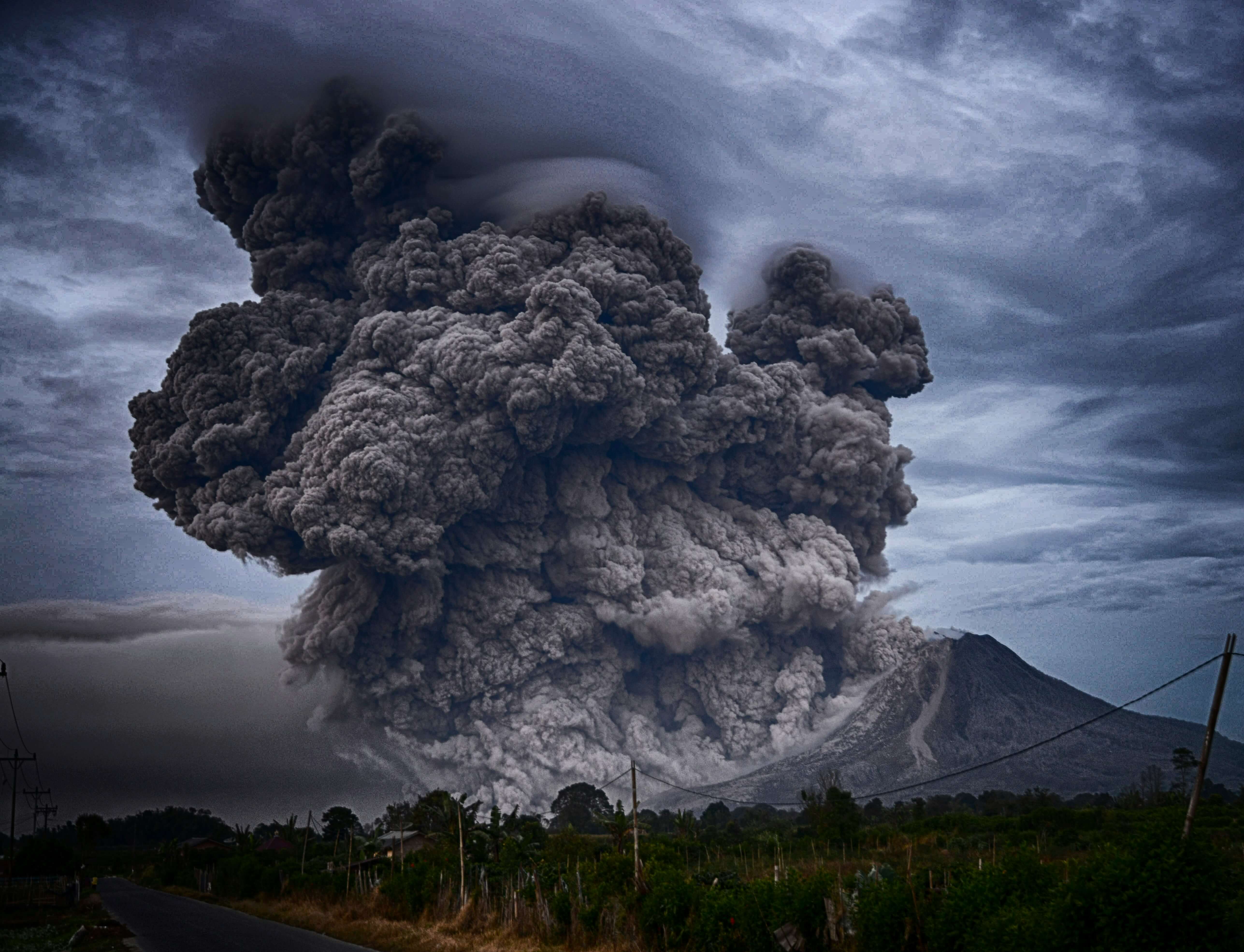 Towering ash plume erupting from a volcano under stormy skies